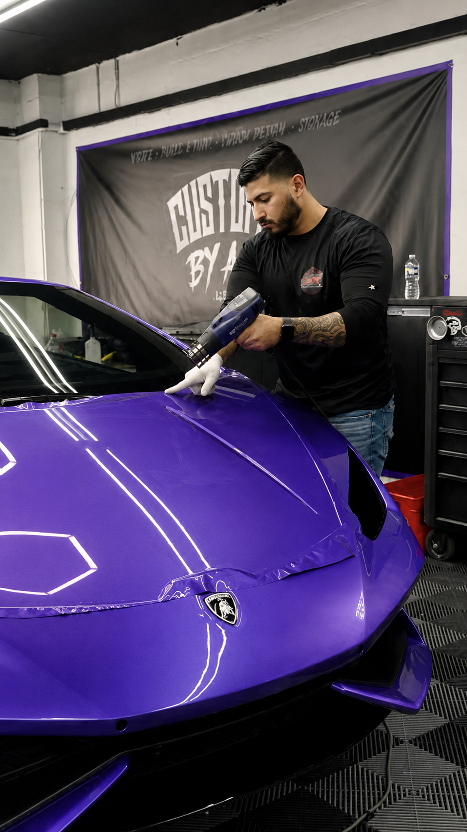 Ali working on a purple Lamborghini color change wrap at the CustomsByAli shop in Elyria, OH