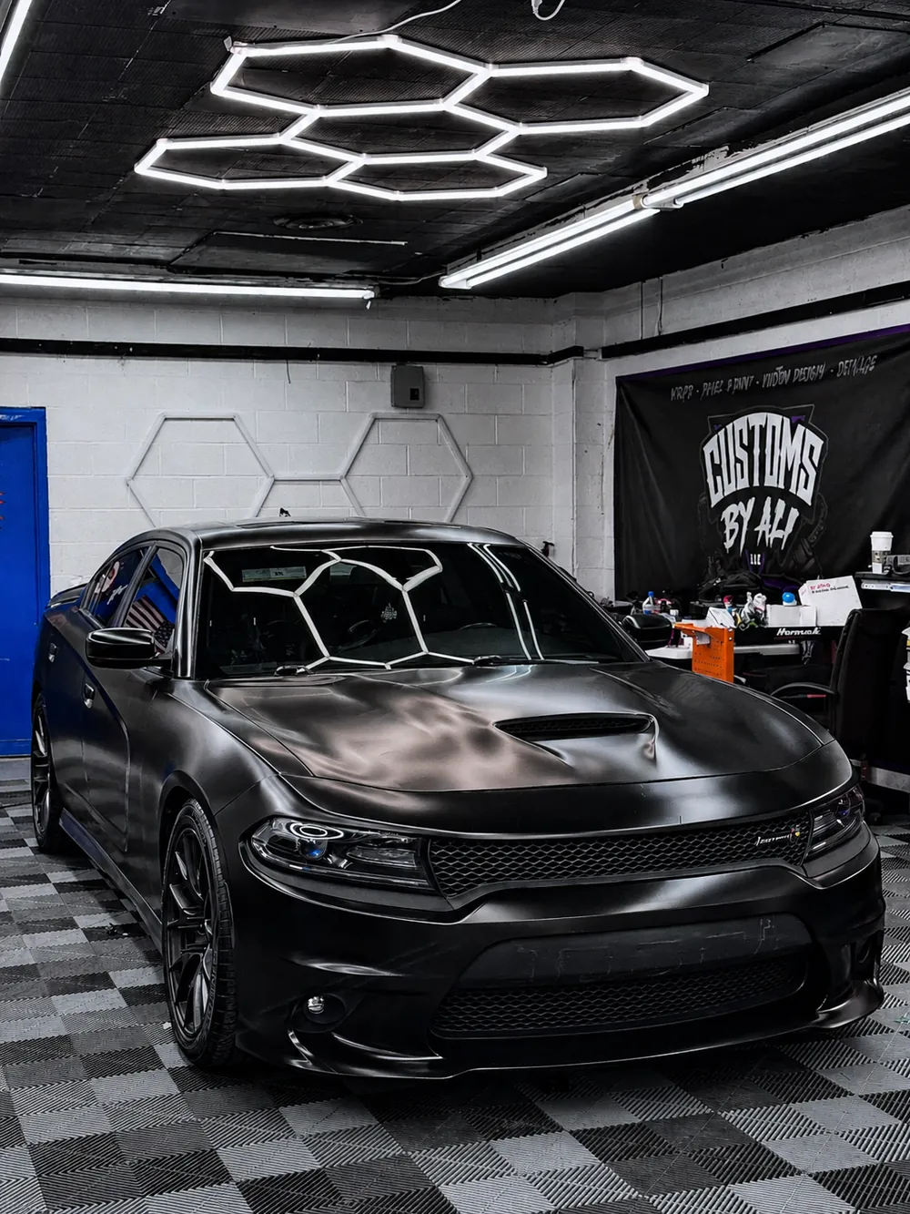 Dodge Charger wrapped in satin black vinyl inside the CustomsByAli shop in Elyria, OH