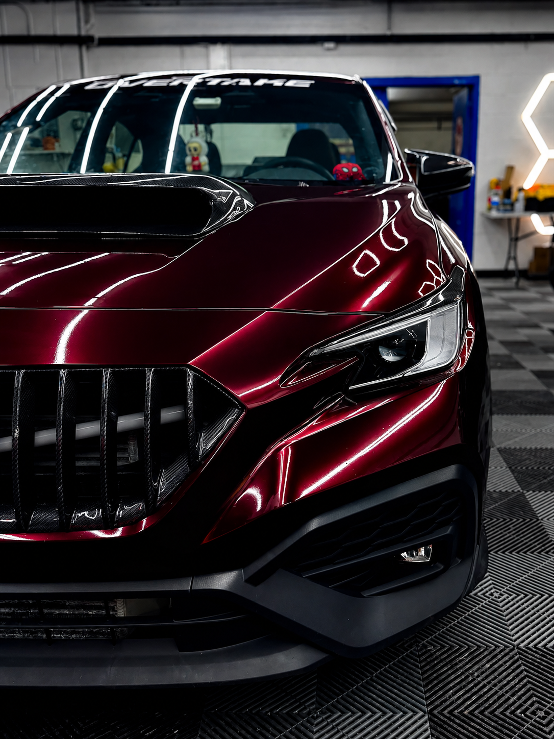 Gloss burgundy red vinyl wrap on a sports sedan inside the CustomsByAli shop in Elyria, OH